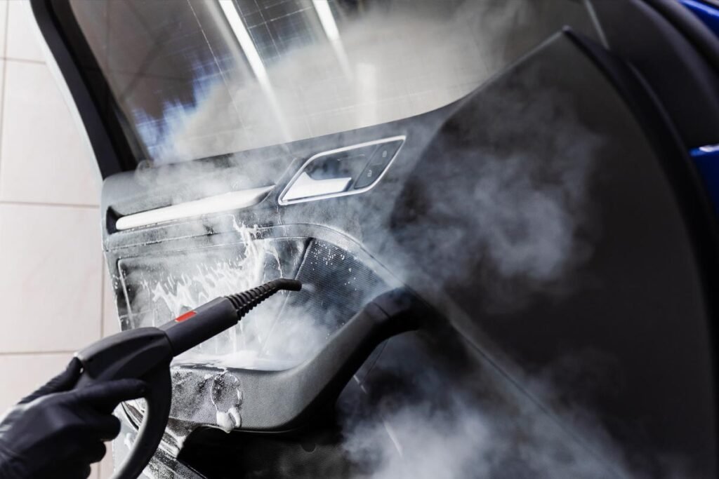 A close-up shot captures a person's hand meticulously washing a red car using a white cloth and soapy water, showcasing the care and attention to detail involved in automotive cleaning. The action is dynamic and highlights the sparkling finish of the car.